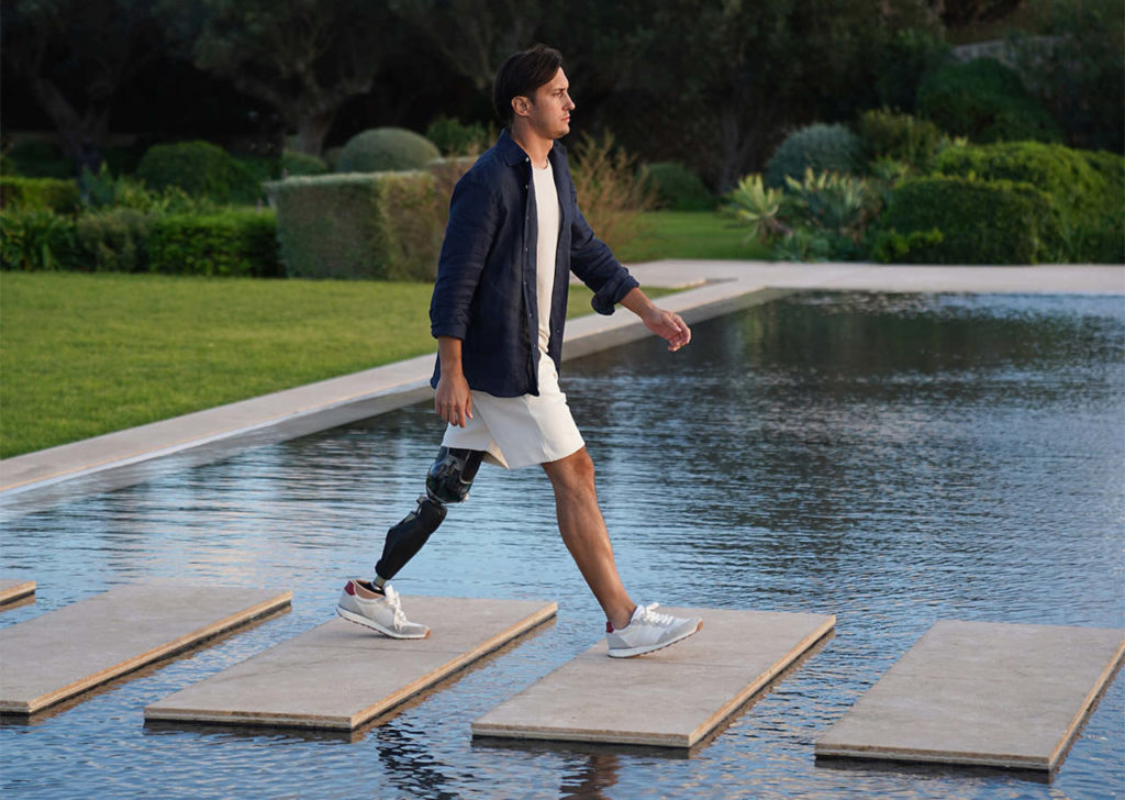 Ein Mann nutzt seine moderne Beinprothese aktiv beim Spaziergang über architektonische Betonflächen am Wasser.