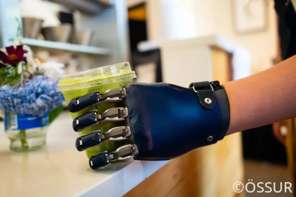 Eine moderne Armprothese im Alltagseinsatz beim gezielten Greifen nach einem Becher.